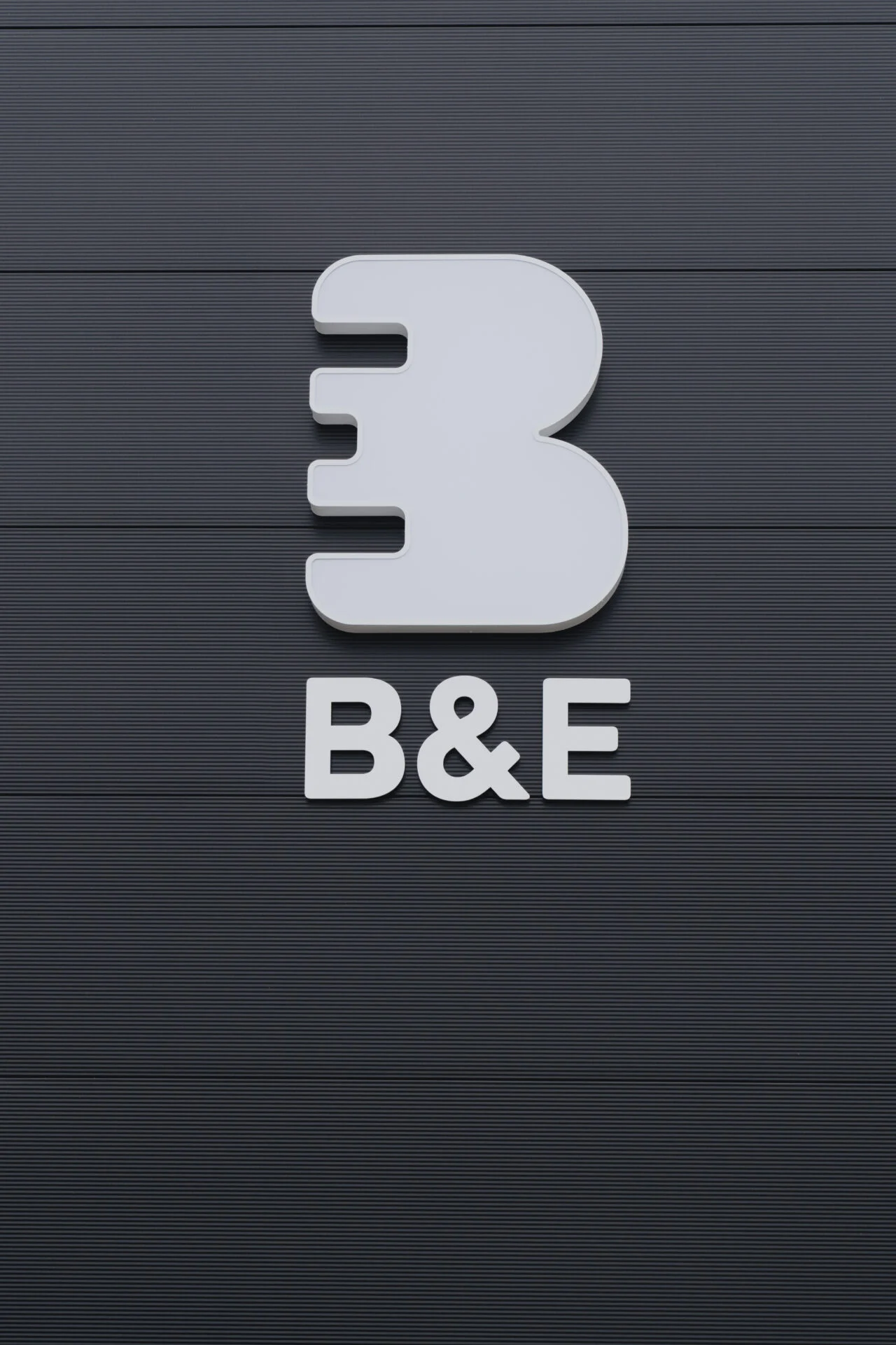 Close-up losse 3D-gevelletters B&E in wit op donkere gevel