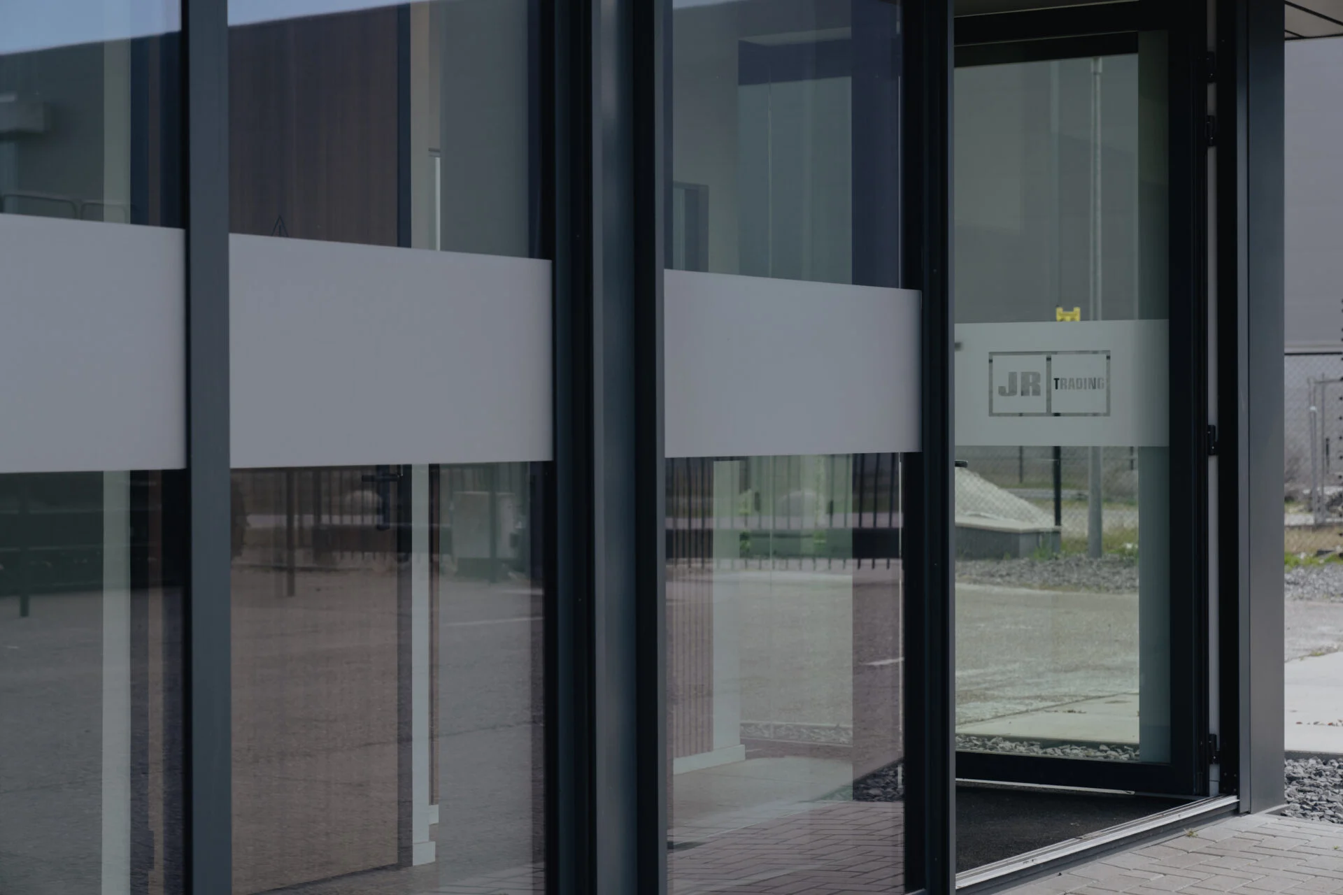 Geëtste raambelettering JR Trading op glazen entreepui