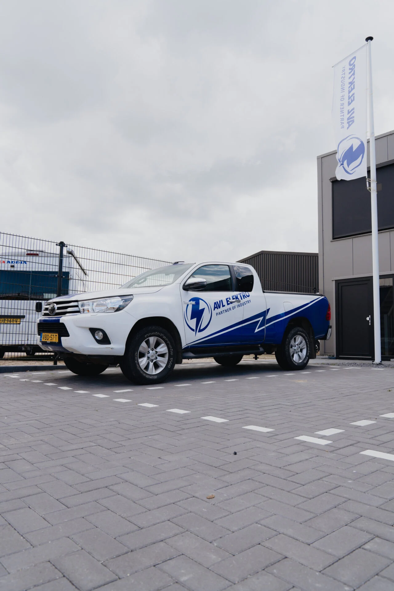 AVL Elektro voertuig en reclamevlag bij bedrijfspand